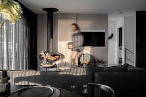 Ein modernes Wohnzimmer mit einer Couch, einem Couchtisch, einem Kamin und einem an der Wand montierten Fernseher.