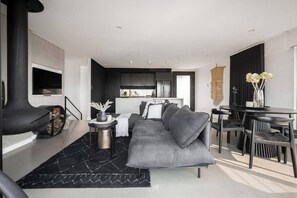 Ein modernes Wohnzimmer mit Sofa, Esstisch und Kamin.