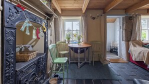 A cozy room with a wooden ceiling, a fireplace, a dining table with chairs, and a bed with a blanket.