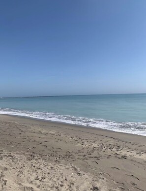 Uma praia com céu claro e águas calmas.