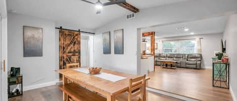 Un salón amplio con una mesa de comedor de madera, un sofá y un ventilador de techo.