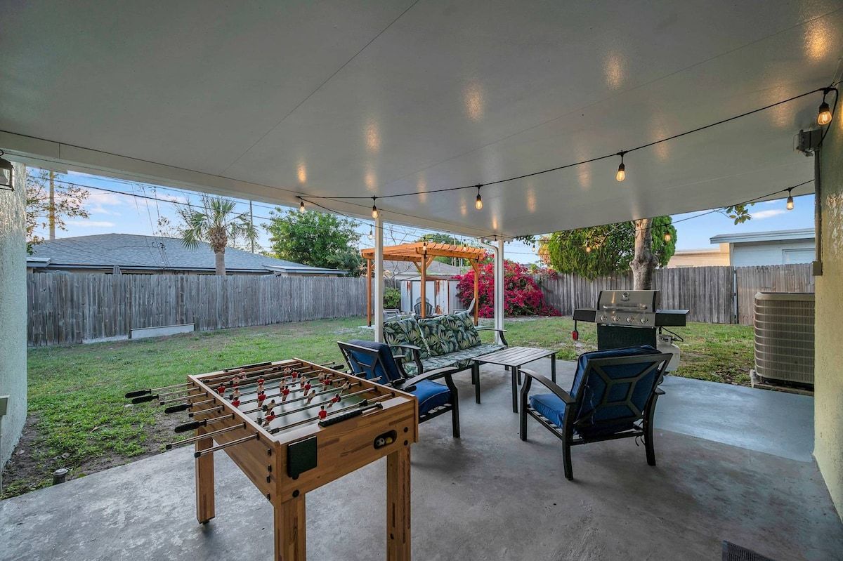 An outdoor patio area with a foosball table, seating, and a pergola.