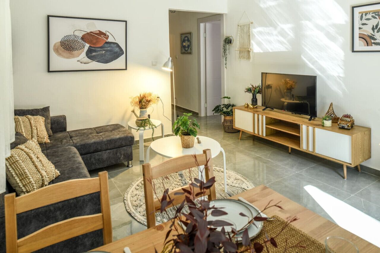 A modern living room with a grey sofa, a round coffee table, and a TV on a wooden stand.