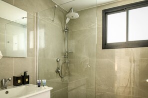 A bathroom with a glass shower enclosure, a white sink, and a large mirror.