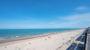 Una spiaggia con cielo sereno, un'area di parcheggio e un cartello che indica 'Piano 1 Mare'.