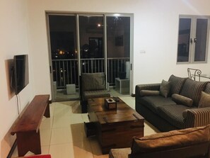 A living room with a sofa, a coffee table, a bench, and a TV.