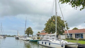 A marina with several sailboats docked, a grassy area, and a building with large windows. - perfect property for watersports enthusiasts (Stavoren)