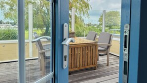A deck with a wooden table and chairs, overlooking a body of water with boats. - perfect property for watersports enthusiasts (Stavoren)