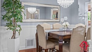 Une salle à manger avec un grand miroir, un lustre et une plante en pot.