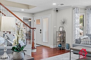 A living room with a staircase, a coffee table, a sofa, and a decorative shelf. - San Gabriel Stunner - An Irvie Home (Albuquerque)