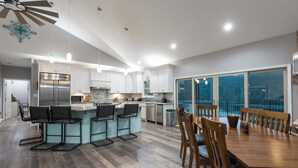 Una cocina moderna con una isla central, taburetes de bar y un comedor con sillas de madera.