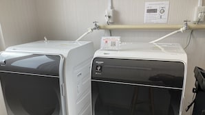 Dos lavadoras de carga frontal con un panel de control, un enchufe de corriente y un código QR para PayPay.