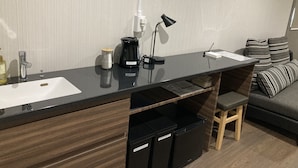 Una kitchenette moderna con un lavamanos, cafetera y armarios de almacenamiento.