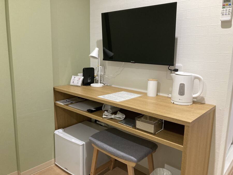 A compact workspace with a desk, chair, and a small refrigerator.