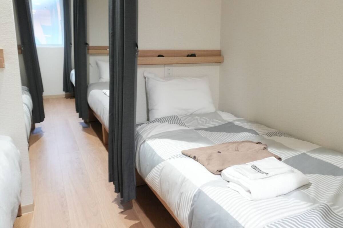 Una cama individual con cabecera de madera, una mesita de noche y una ventana con cortinas.