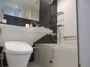 A modern bathroom with a white toilet, a sink with a mirror above, and a shower area.