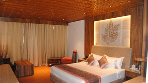 A spacious hotel room with a large bed, wooden flooring, a wooden ceiling, and a decorative wall panel. - Hotel Green Top (Udhampur)