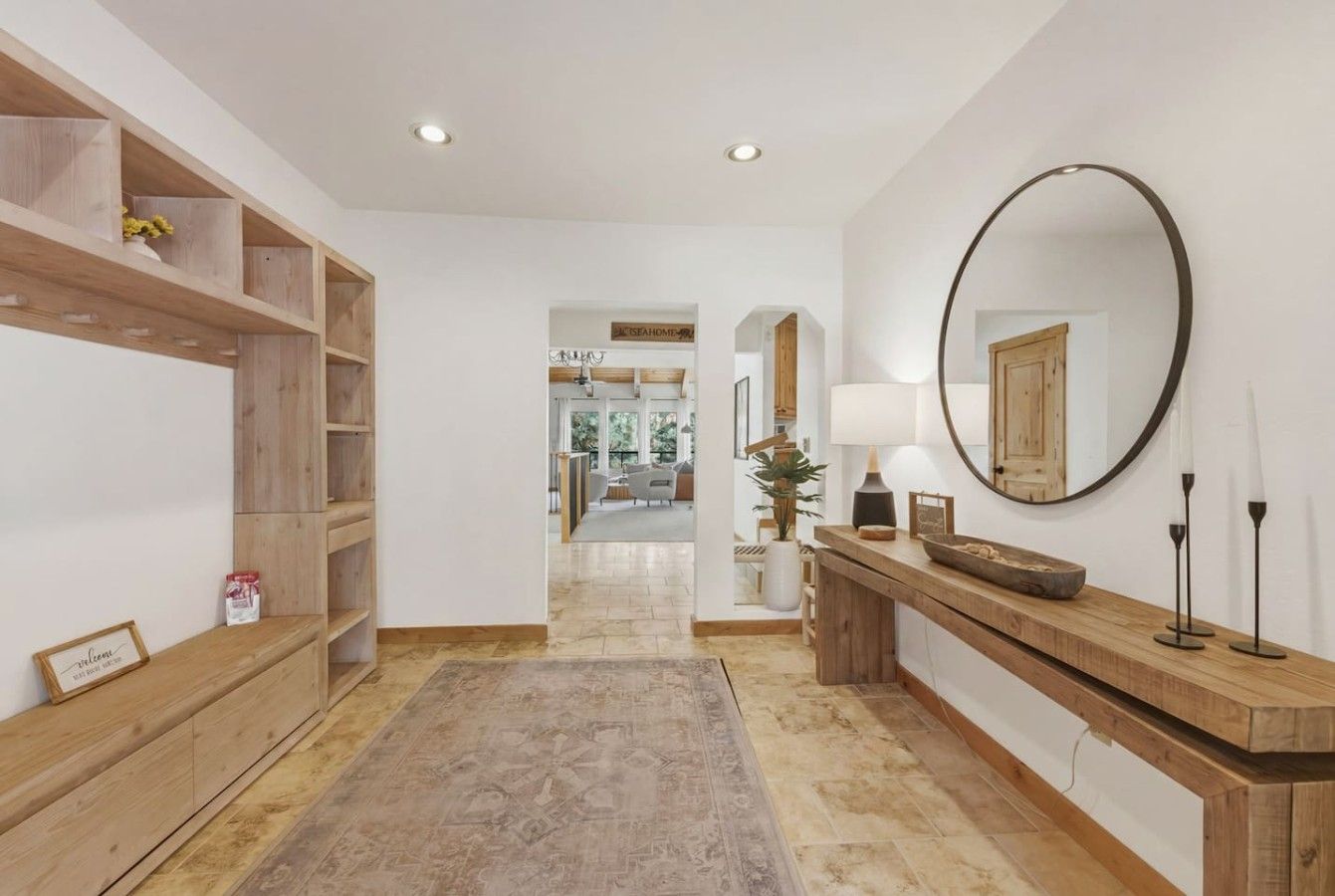 A hallway with a wooden bench, a mirror, and a console table with a lamp.