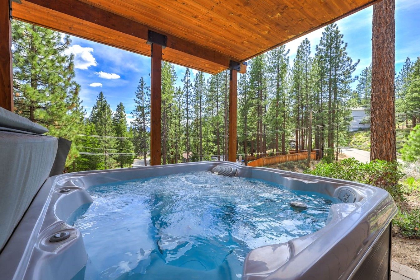 A hot tub in a covered outdoor area with a view of a forest.