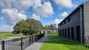 A pathway leading to a building with a metal fence on one side and a grassy area on the other. - Large modern holiday home with pool close to the beach (Groede)