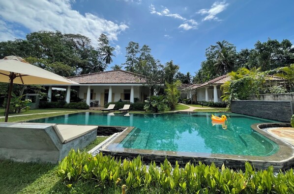 Een buitenzwembad, parasols bij het zwembad en ligstoelen