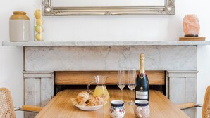 A dining table with a bottle of Bollerenger champagne, a pitcher of orange juice, and a bowl of pastries. - The Barnsbury, London Apartment w/WIFI (London)