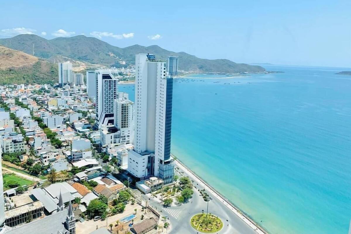 Un paysage urbain côtier avec des immeubles modernes de grande hauteur, une marina et une vue dégagée sur l’océan.