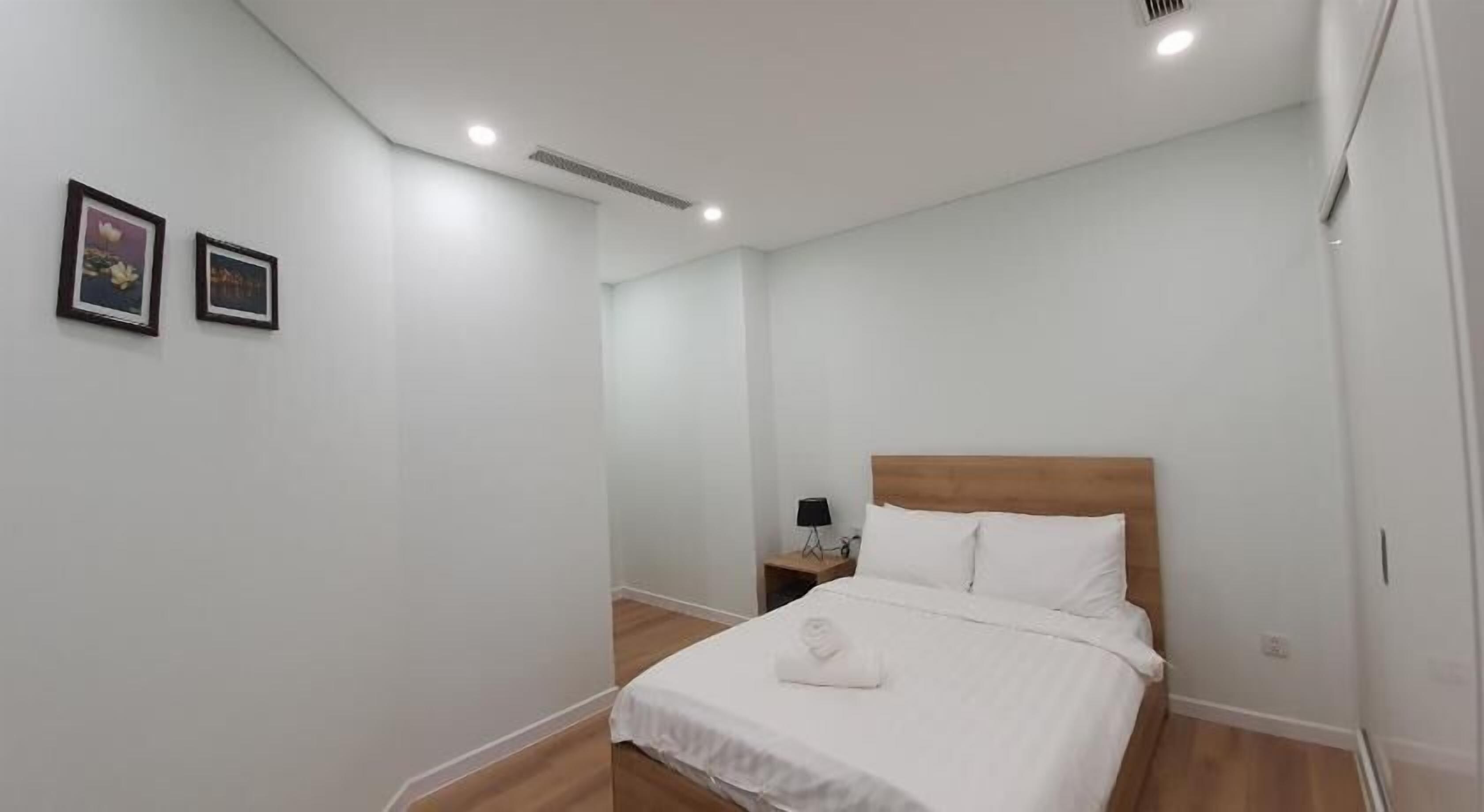 Una camera da letto con una testiera in legno, un letto rifatto con cura e due quadri appesi alla parete.