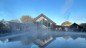 Un edificio moderno con fachada de vidrio, rodeado por una piscina tranquila y reflectante.