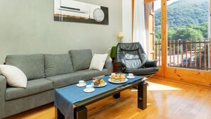 Un salon avec un canapé gris, un fauteuil en cuir noir et une table basse sur laquelle sont disposées des pâtisseries.