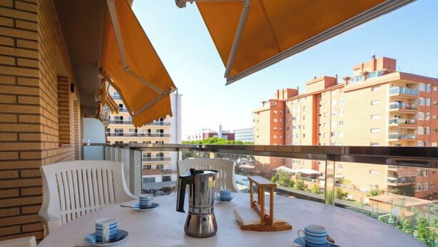 Ein Balkon mit Frühstückstisch, Kaffeekanne und Blick auf Wohnhäuser.