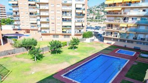 Ein Wohngebäude mit Swimmingpool, grünen Rasenflächen und einer Hügelkulisse im Hintergrund.