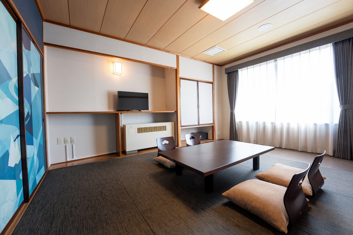 Ein modernes Hotelzimmer mit einem großen Bett, einem Schreibtisch und einem Fernseher.