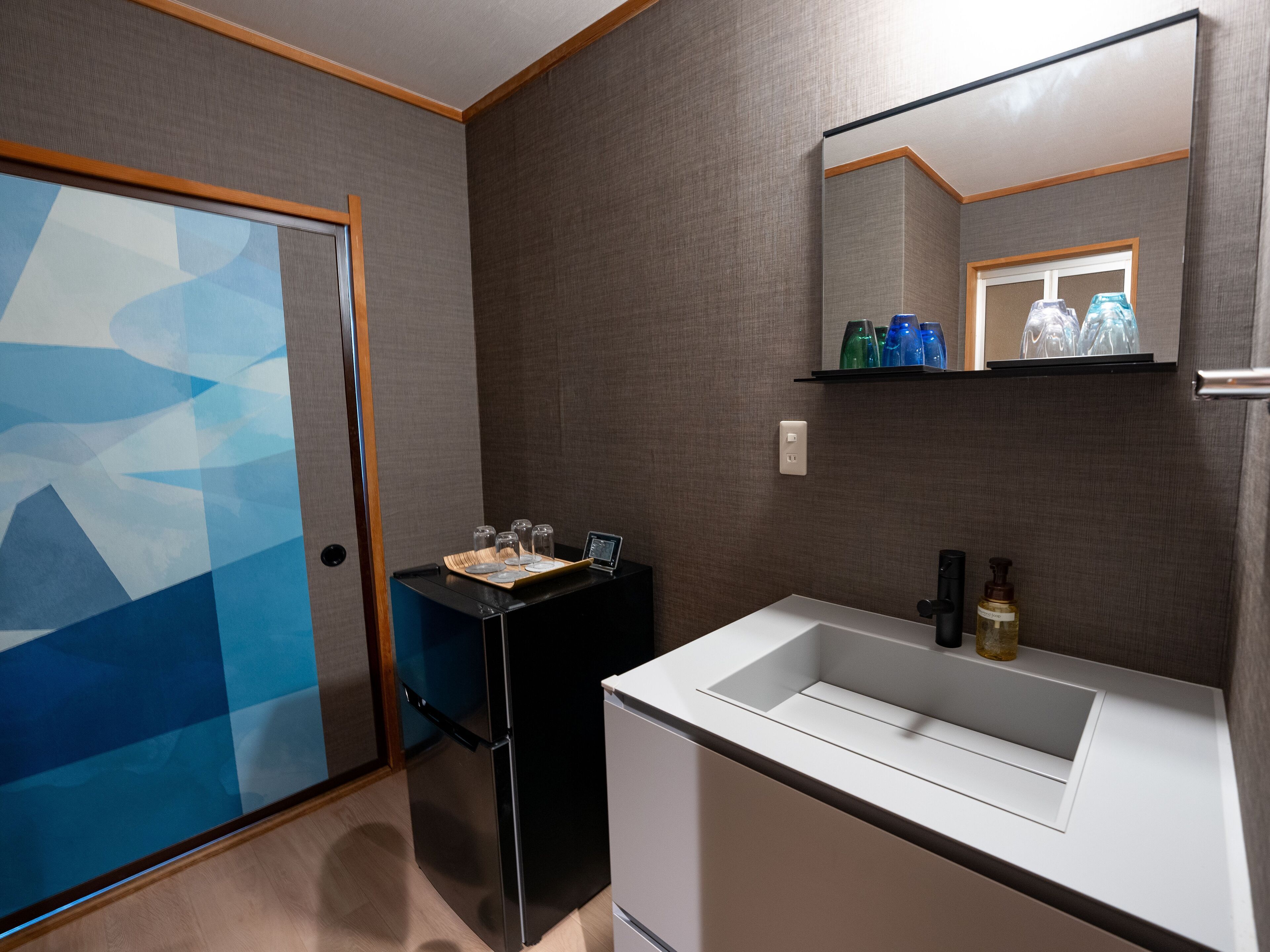 A modern bathroom with a glass shower door, a black vanity, a white sink, and a mirror above the sink.