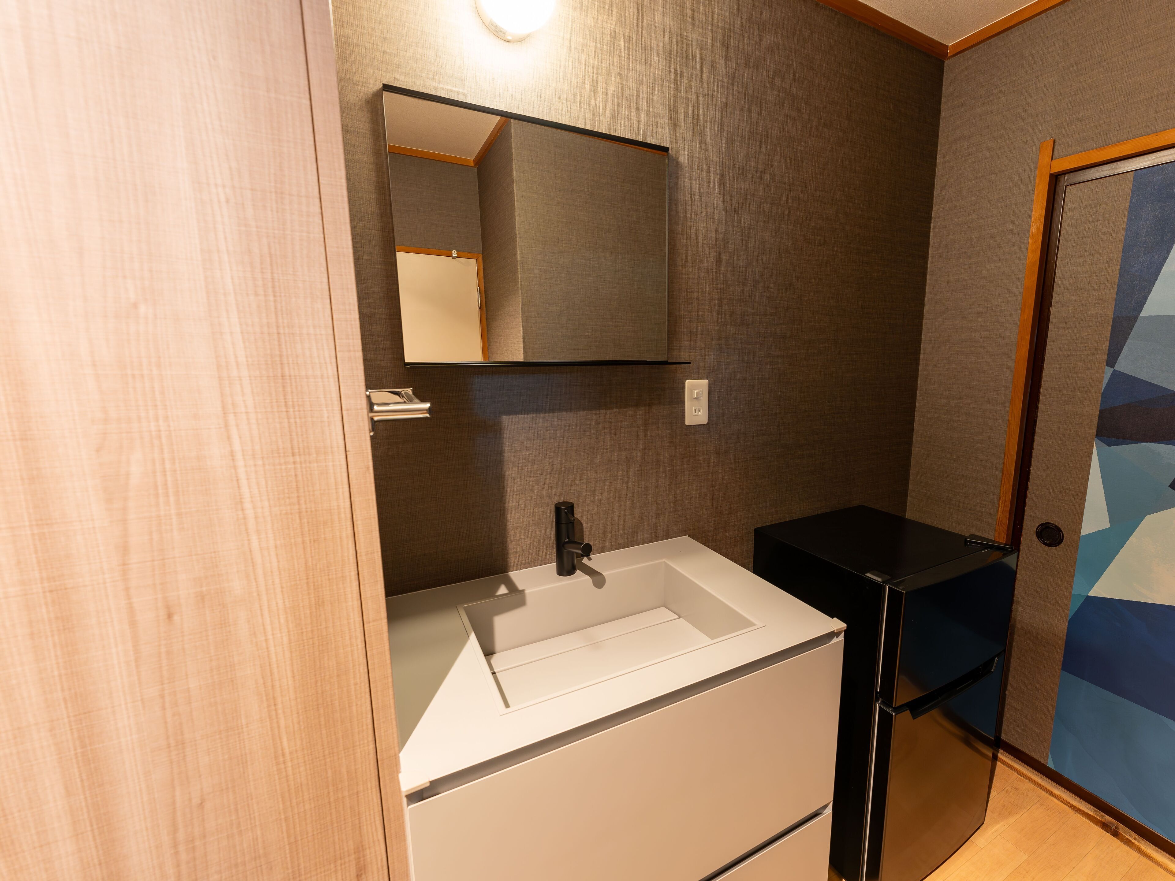 A bathroom with a white sink, a mirror, and a black cabinet.