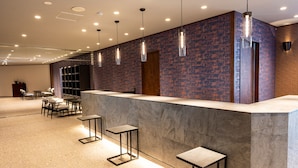 A modern reception area with a counter, bar stools, and pendant lighting.