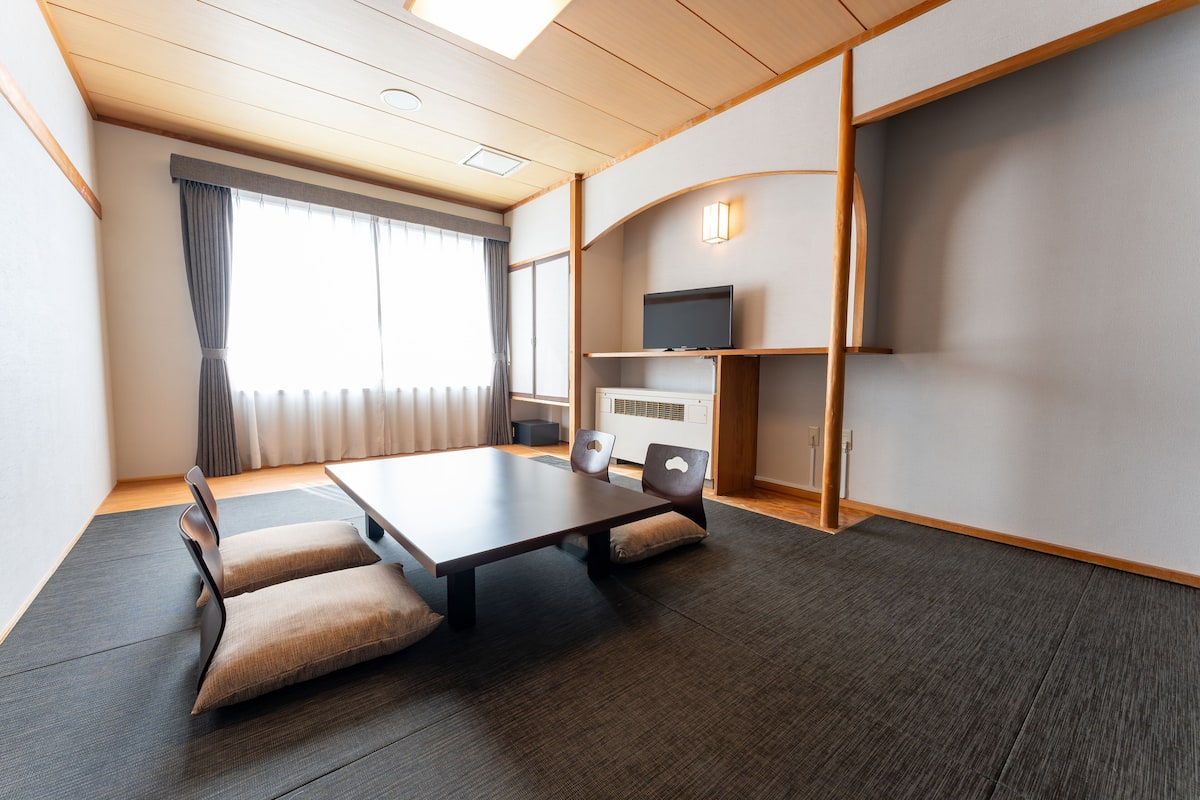Ein modernes Hotelzimmer mit einem großen Bett, einem Flachbildfernseher, einem Schreibtisch und einer Sitzecke mit Kissen.