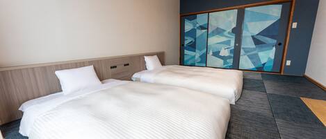 Una habitación de hotel con dos camas, cabecera de madera, una gran obra de arte abstracta en la pared y una puerta corredera con diseños geométricos.