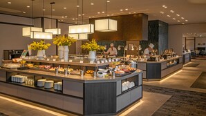 A modern buffet setup with multiple food stations, overhead lighting, and a clean, organized layout.