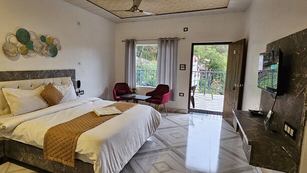 Quarto de hotel com cama, escrivaninha, cadeira, TV e varanda com vista.