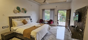A hotel room with a bed, a desk, a chair, a TV, and a balcony with a view. - Cloud Forest (Lansdowne)