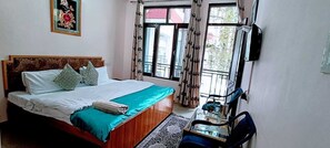 A bedroom with a bed, a desk, and a window with curtains.