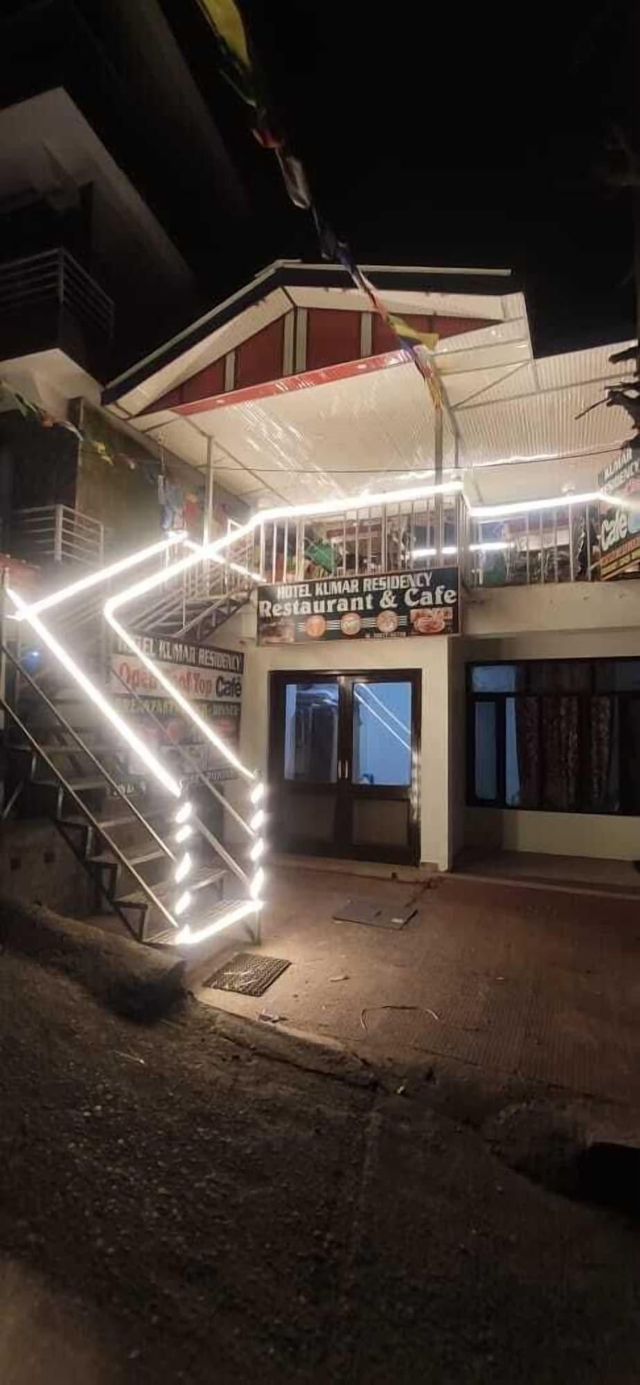 A hotel with a sign for 'Hotel Kumar Residency Restaurant & Cafe,' a staircase, and a covered entrance.