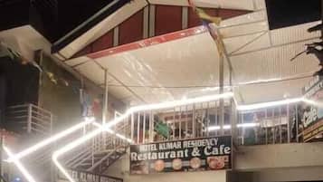 A hotel with a sign for 'Hotel Kumar Residency Restaurant & Cafe,' a staircase, and a covered entrance.