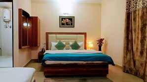 Una habitación de hotel con cama, mesita de noche, lámpara y un cuadro en la pared.