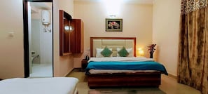 A hotel room with a bed, bedside table, lamp, and a picture on the wall. - Kumar Residency (Dharamshala)
