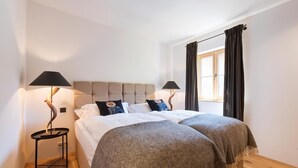 Une chambre avec un grand lit, deux lampes de chevet, une fenêtre avec des rideaux et un plancher en bois.
