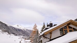 Un paysage montagneux enneigé, avec un bâtiment doté de grandes fenêtres et d’un toit en bois.