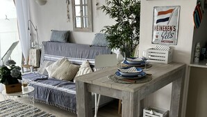 A cozy living room with a wooden coffee table, a sofa, and a large window. - BEACH LOFT with fantastic view over the Mediterranean and Palamos. (Sant Antoni de Calonge)