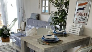 A dining area with a wooden table, white chairs, and a blue and white patterned table runner. - BEACH LOFT with fantastic view over the Mediterranean and Palamos. (Sant Antoni de Calonge)